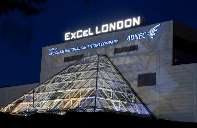 Modern exterior of ExCeL London at night featuring the illuminated glass pyramid entrance and Royal Docks skyline - My London Transfer
